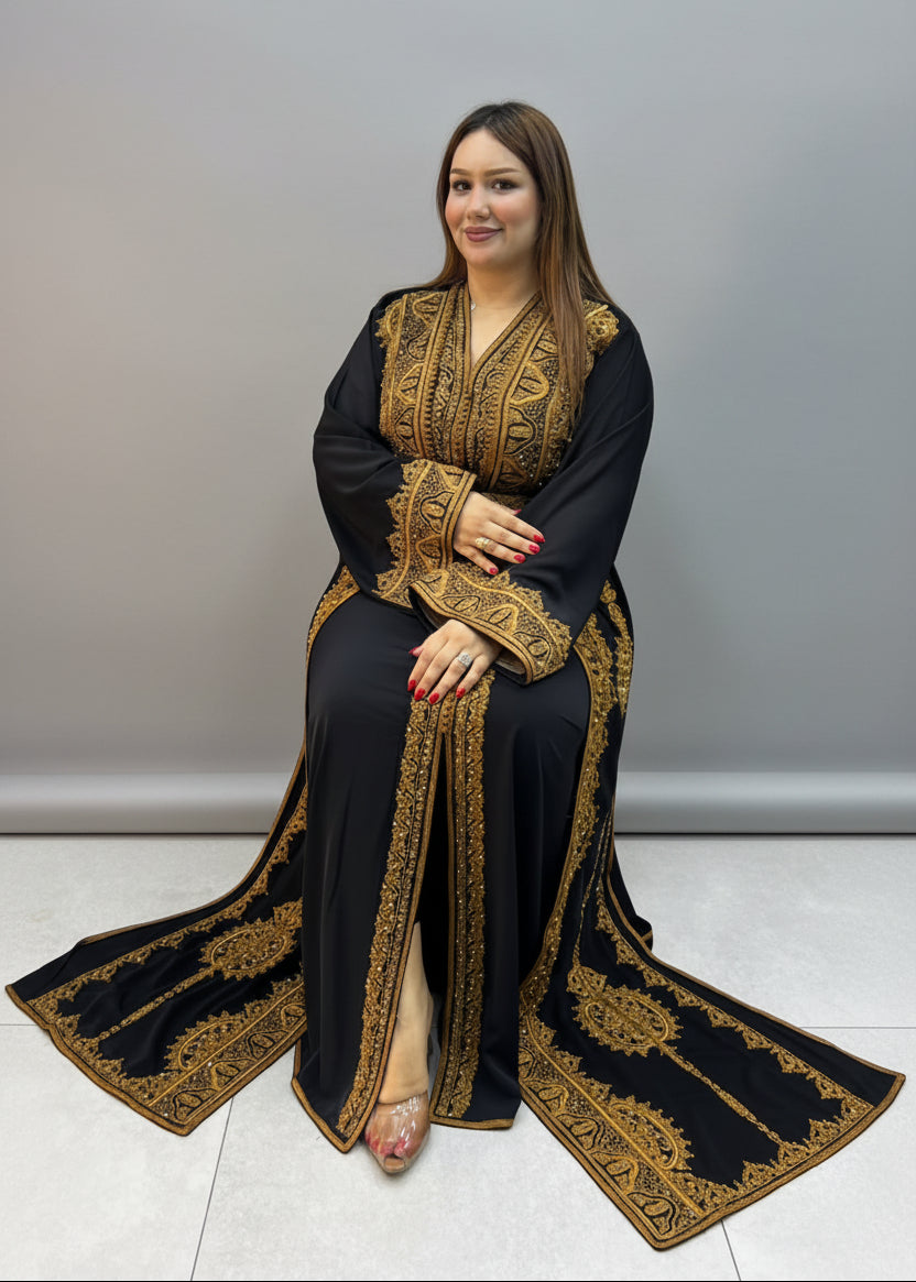 A woman wearing a black traditional long Kaftan with ornate gold embroidery.