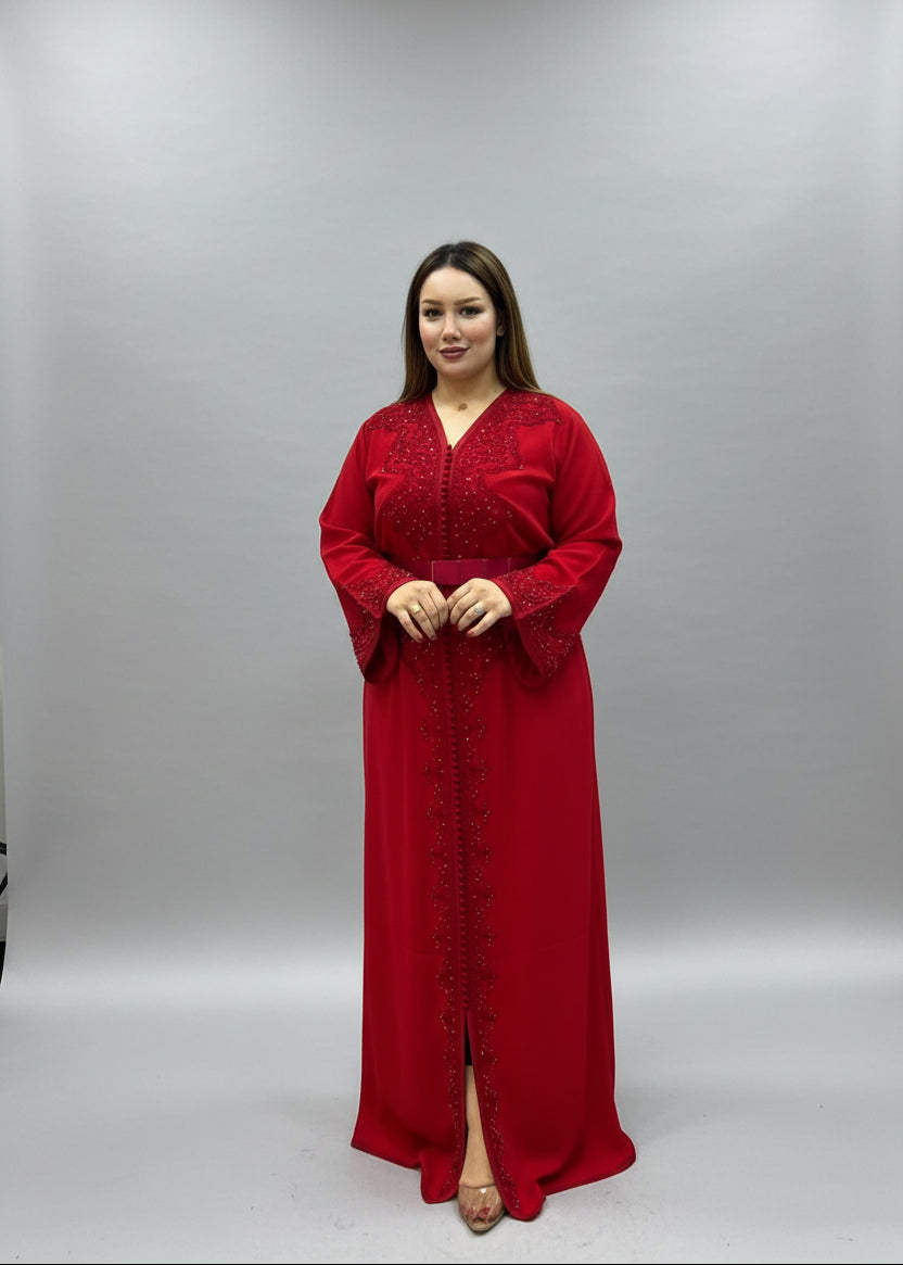 A woman wearing a long red embroidered Caftan stands .