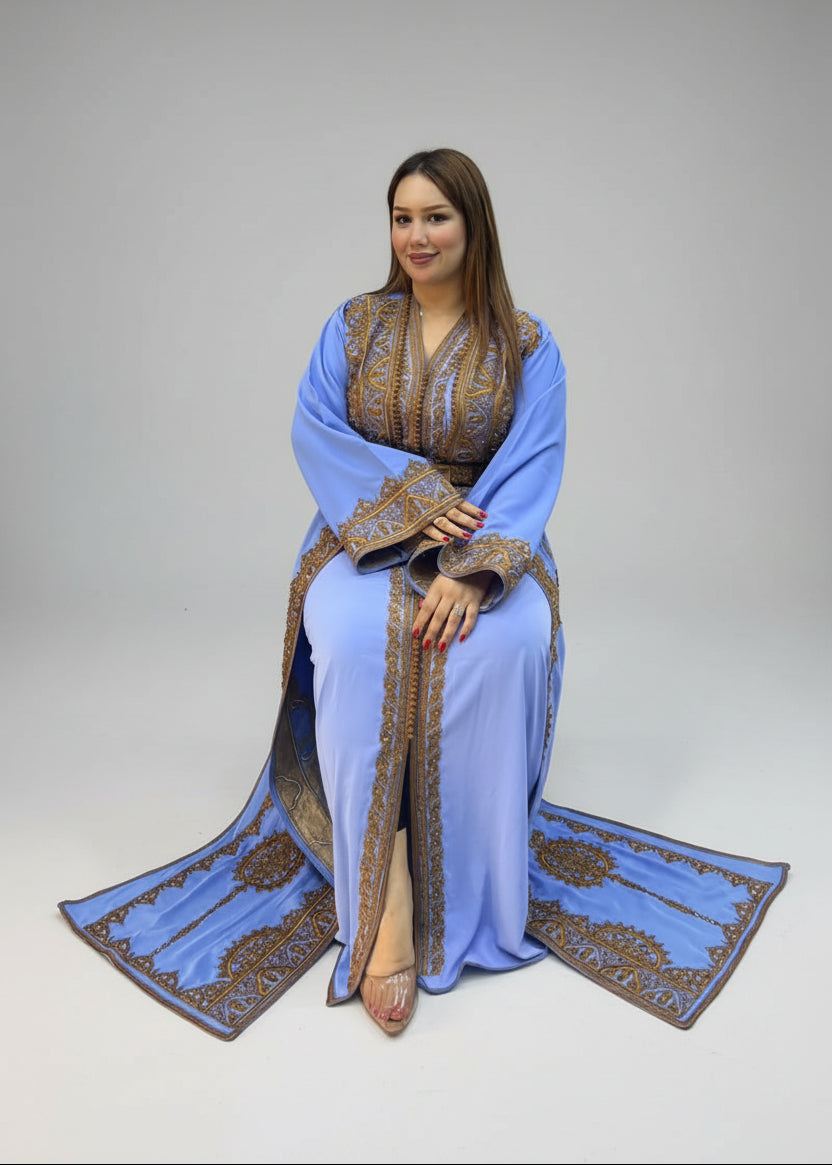 A woman wearing a light blue Moroccan caftan with ornate gold embroidery.