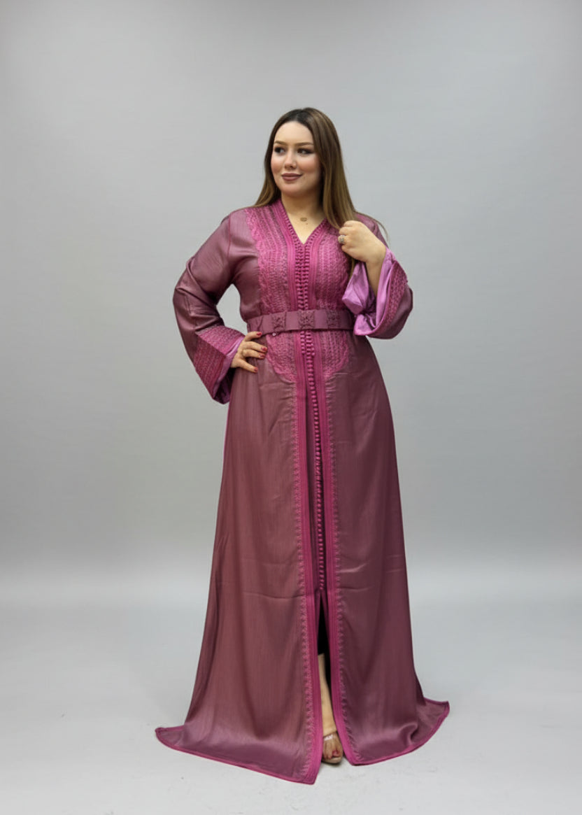 A woman modeling a long magenta-purple kaftan dress with pink trim .