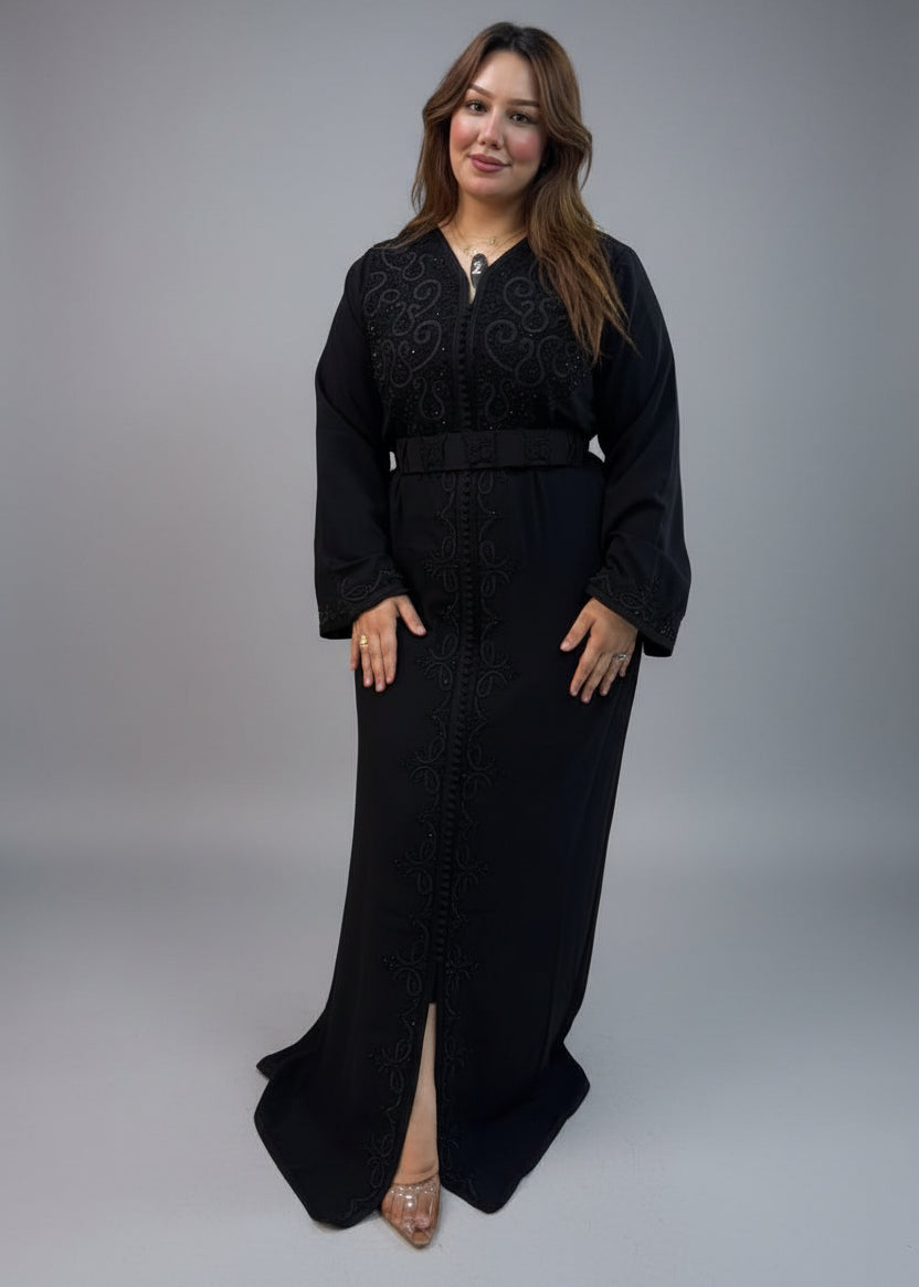 A woman modeling a long black embroidered moroccan caftan .