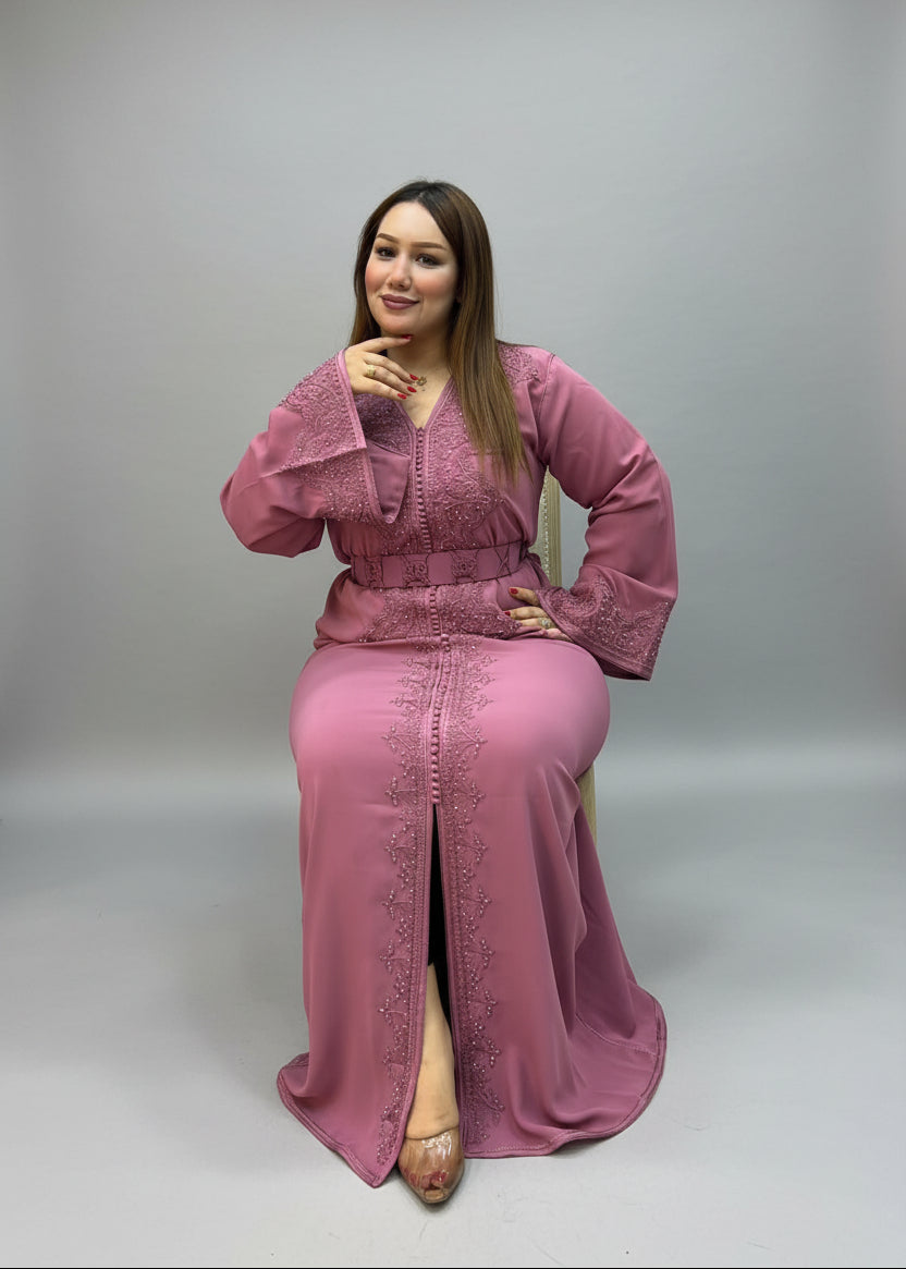 A woman modeling a dusty pink embroidered long kaftan .
