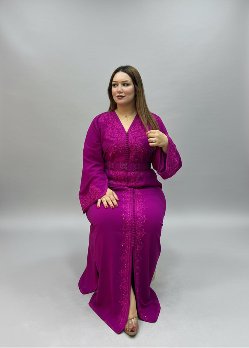 A woman wearing a bright magenta-purple embroidered kaftan dress.