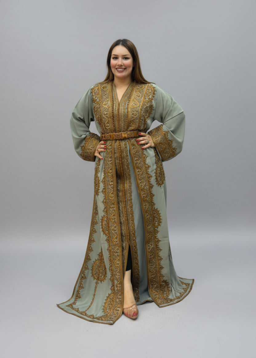 A woman modeling a sage green and gold embroidered kaftan dress .