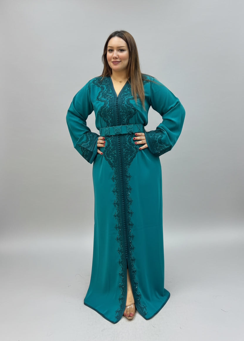 A woman modeling a long teal green embroidered caftan .