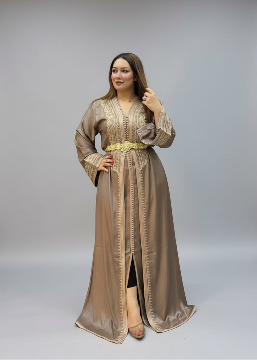 A woman modeling a long taupe-beige embroidered kaftan with a gold belt.