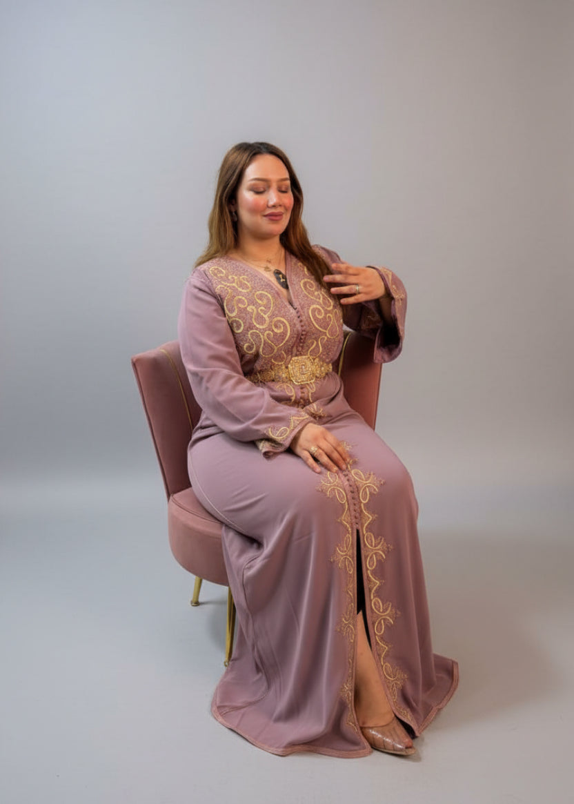 A woman wearing a dusty mauve moroccan caftan with gold embroidery