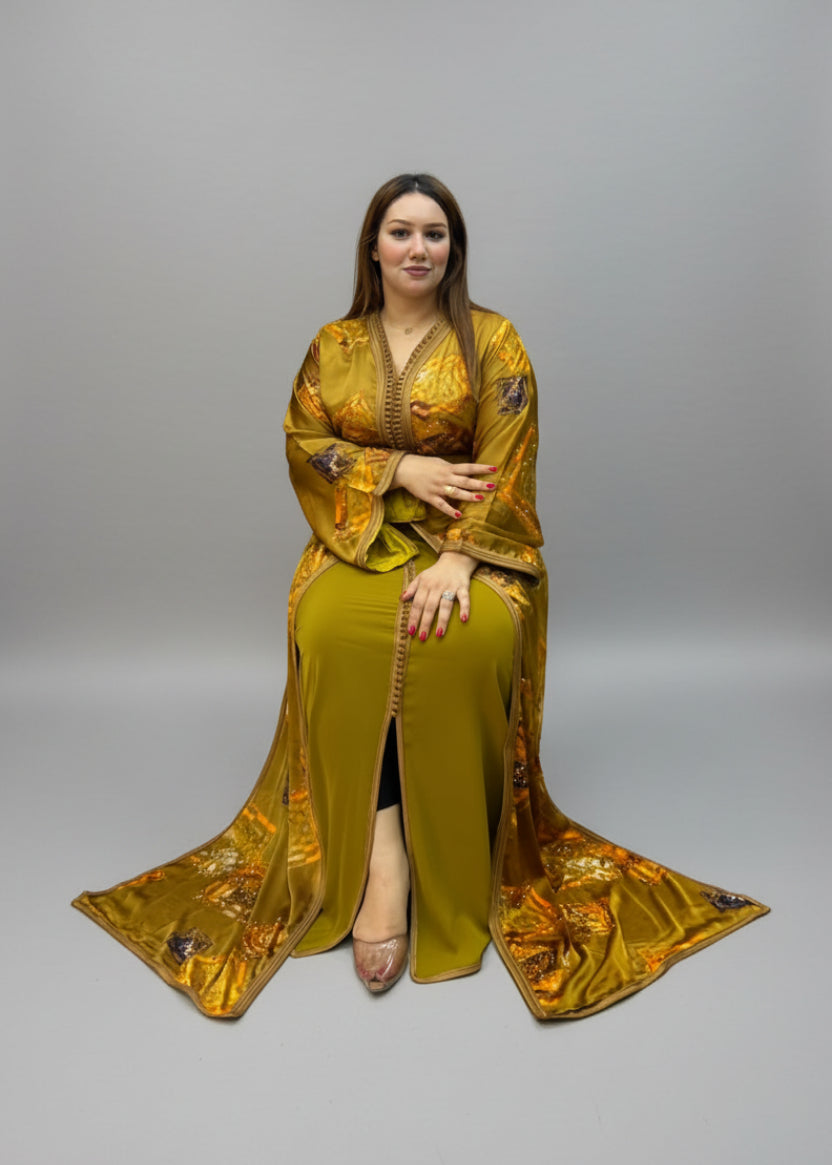A woman wearing a long, flowing golden yellow kaftan with metallic gold embroidery and a matching headscarf.