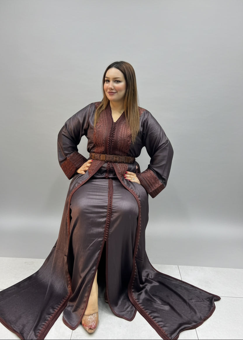 A woman wearing a dark brown satin caftan with a matching belt and long draped train.