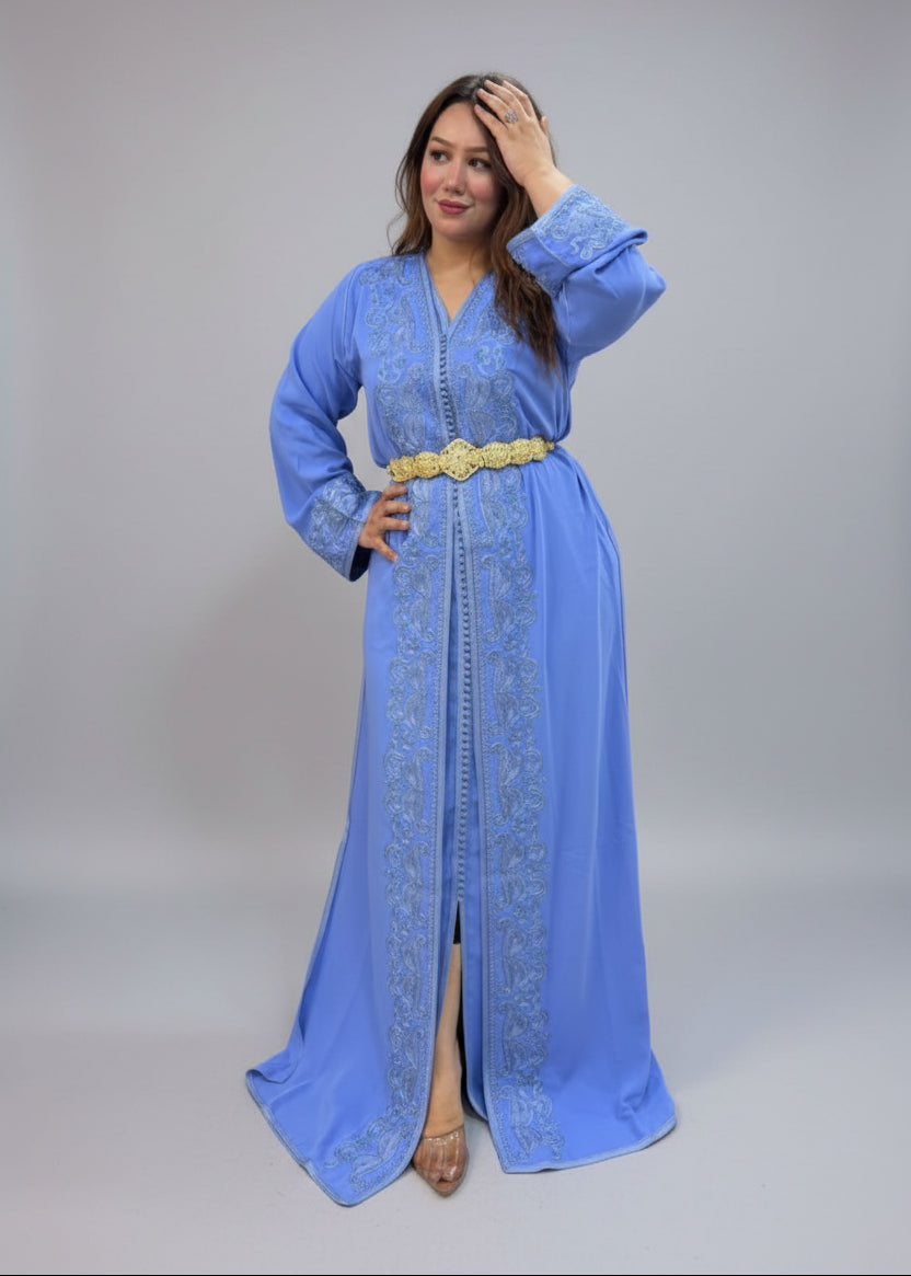 A woman modeling a long light blue embroidered kaftan with a gold belt.