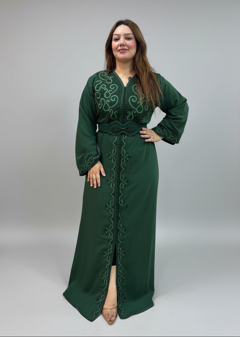 A woman modeling a dark green long moroccan kaftan with intricate embroidery and a matching belt.