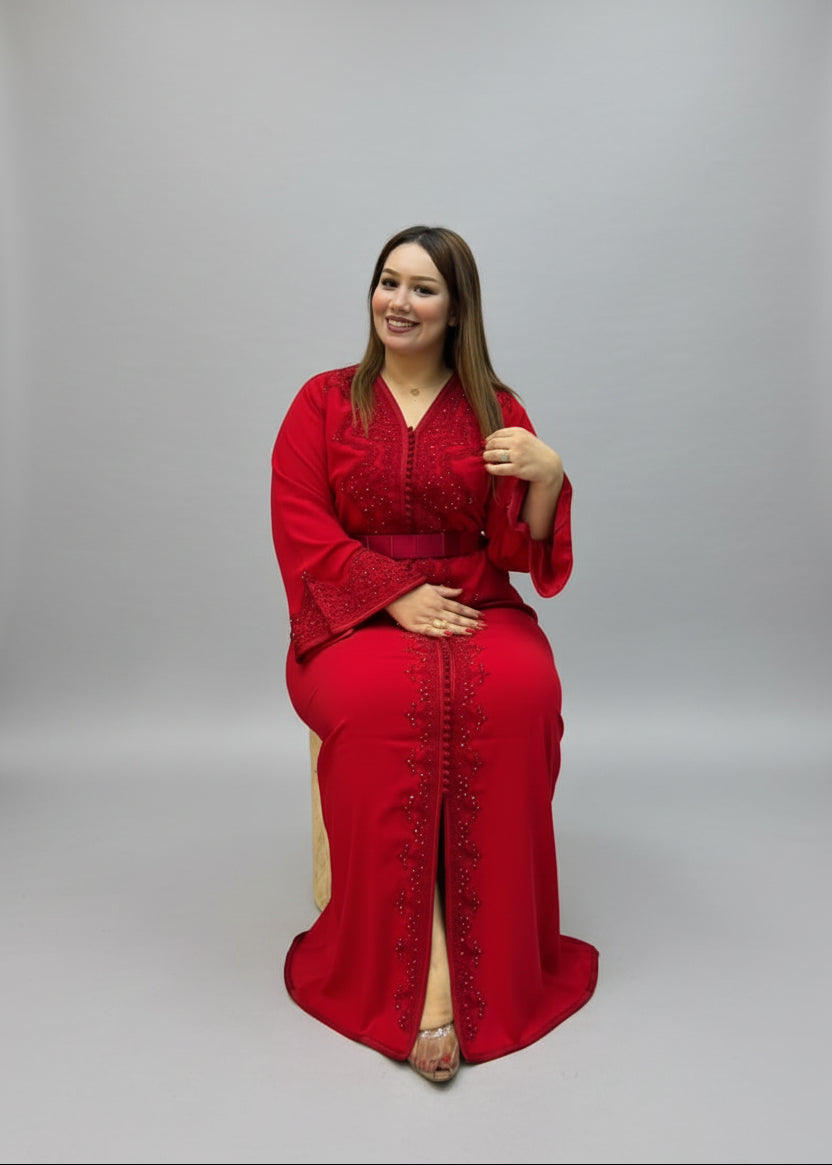 A woman wearing a vibrant red embroidered kaftan with a matching belt and long sleeves.