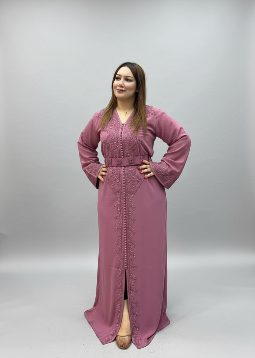 A woman modeling a dusty pink embroidered long Caftan .