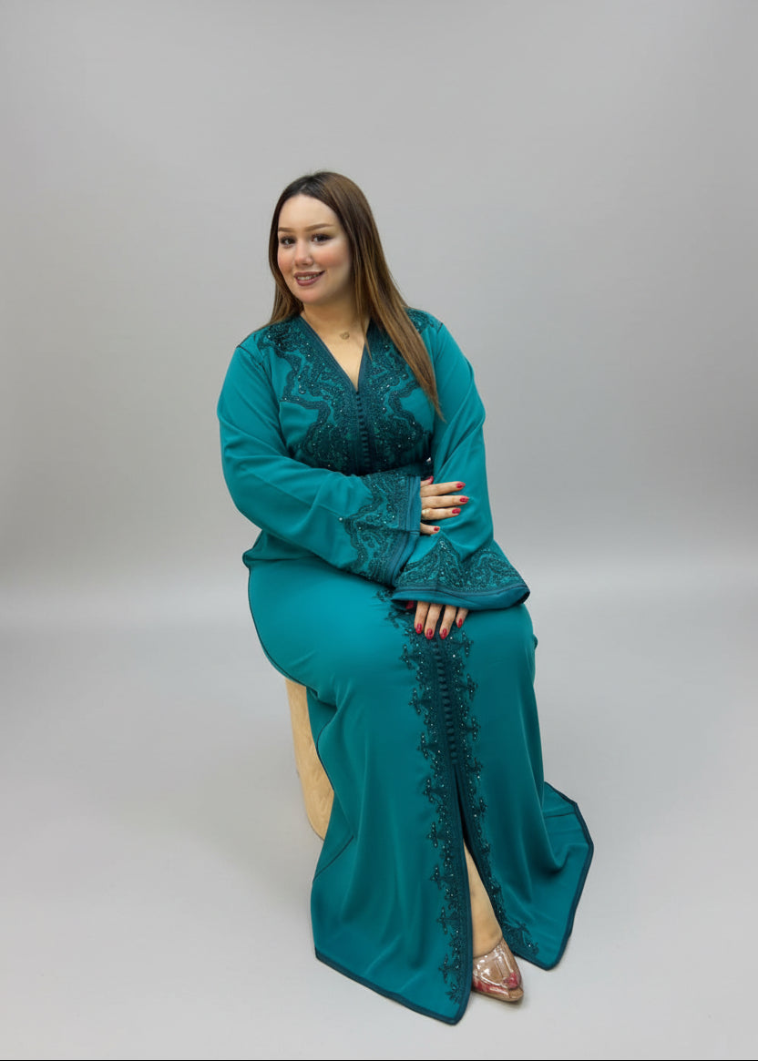 A woman wearing a teal green embroidered long Kaftan .
