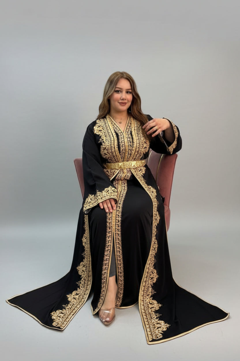 Woman wearing an ornate black and gold dress in a store setting. "caftan dress"
"women's caftan"
"kaftan"
"cotton caftan"
"caftan moroccan"
"moroccan caftan"
"caftan for women"
"white caftan"
"blue caftan"
"what is caftan"
"caftan dresses"
"silk caftan"
"vintage caftan"
"maxi dress"
"beach caftan"
"caftan maxi dress"
"caftan for men"
"what is a caftan"
"caftan cover up"
"kaftan dress"
"plus size caftan"
"caftan plus size"
"short caftan"
"linen caftan"
"womens caftan"
"caftan meaning"
"caftan pattern"