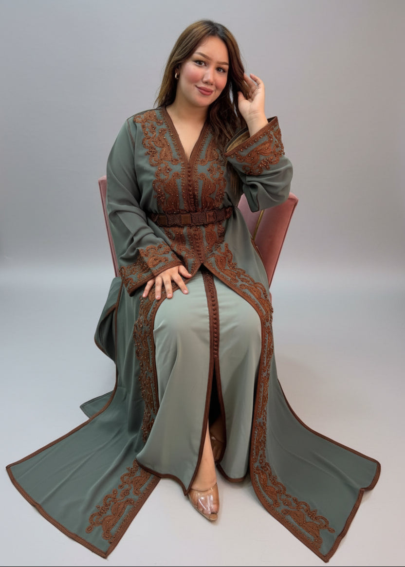 A woman wearing a sage green Kaftan with brown embroidered patterns.