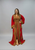 A woman modeling a long red kaftan dress with intricate gold embroidery, 