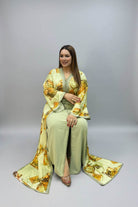 A woman wearing a sage green and gold printed traditional kaftan.