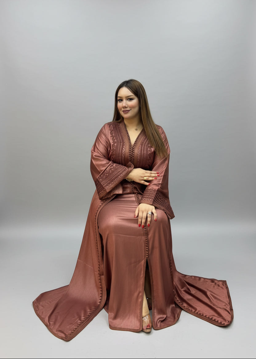 A woman wearing a long, flowing rust-brown satin caftan 