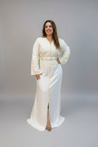 A woman modeling a cream-colored traditional Moroccan kaftan with a matching belt