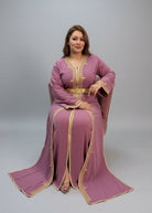Woman in a pink traditional outfit with gold accents sitting in a store. "caftan dress"
"women's caftan"
"kaftan"
"cotton caftan"
"caftan moroccan"
"moroccan caftan"
"men's caftan"
"caftan for women"
"white caftan"
"blue caftan"
"what is caftan"
"caftan dresses"
"caftan men"
"silk caftan"
"vintage caftan"
"maxi dress"
"beach caftan"
"caftan maxi dress"
"caftan for men"
"what is a caftan"
"caftan cover up"
"kaftan dress"
"plus size caftan"
"caftan plus size"
"short caftan"
"linen caftan"
"womens caftan"