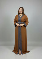 Woman wearing a long brown dress with intricate patterns in a fabric store.
"caftan dress"
"women's caftan"
"kaftan"
