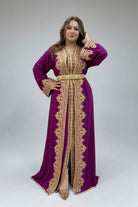 Woman wearing a purple caftan with gold embroidery in a clothing store.