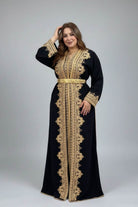 Woman wearing a black and gold embroidered Kaftan in a traditional caftan store .
