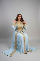 Woman wearing a light blue dress with gold embroidery in a store "caftan dress"
"women's caftan"
"kaftan"
"cotton caftan"
"caftan moroccan"
"moroccan caftan"
"caftan for women"
"white caftan"
"blue caftan"
"what is caftan"
"caftan dresses"
"silk caftan"
"vintage caftan"
"maxi dress"
"beach caftan"
"caftan maxi dress"
"caftan for men"
"what is a caftan"
"caftan cover up"
"kaftan dress"
"plus size caftan"
"caftan plus size"
"short caftan"
"linen caftan"
"womens caftan"
"caftan meaning"