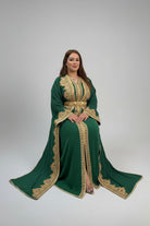 Woman wearing a green dress with gold embroidery in a store setting.

"caftan dress"
"women's caftan"
"kaftan"
"cotton caftan"
"caftan moroccan"
"moroccan caftan"
"men's caftan"
"caftan for women"
"white caftan"
"blue caftan"
"what is caftan"
"caftan dresses"
"silk caftan"
"vintage caftan"
"maxi dress"
"beach caftan"
"caftan maxi dress"
"caftan for men"
"what is a caftan"
"caftan cover up"
"kaftan dress"
"plus size caftan"
"caftan plus size"
"short caftan"
"linen caftan"
"womens caftan"
"caftan meaning"