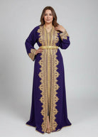 Woman wearing a purple moroccan caftan with gold embroidery in a kaftan store.
