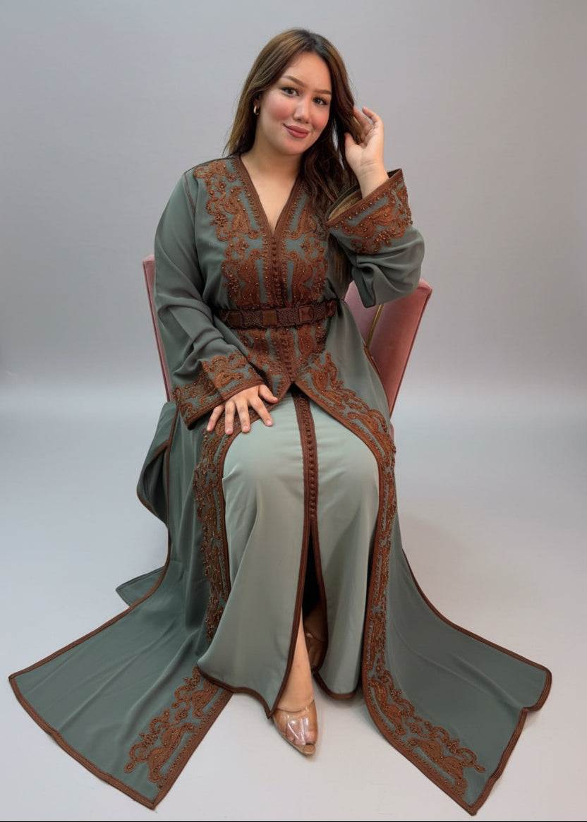 A woman wearing a sage green Kaftan with brown embroidered patterns.
